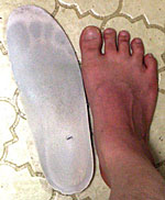 写真：靴の中敷についた足型と、その足型をつけた足